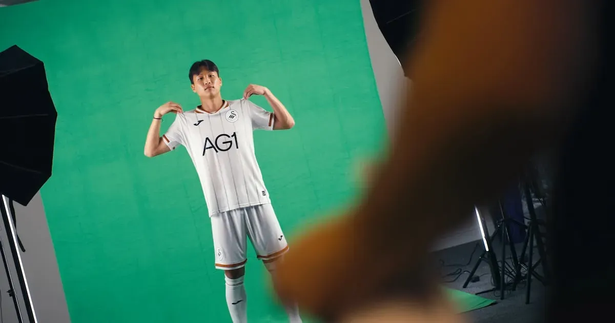 A Swansea City player in the club's white home shirt with AG1 across the front