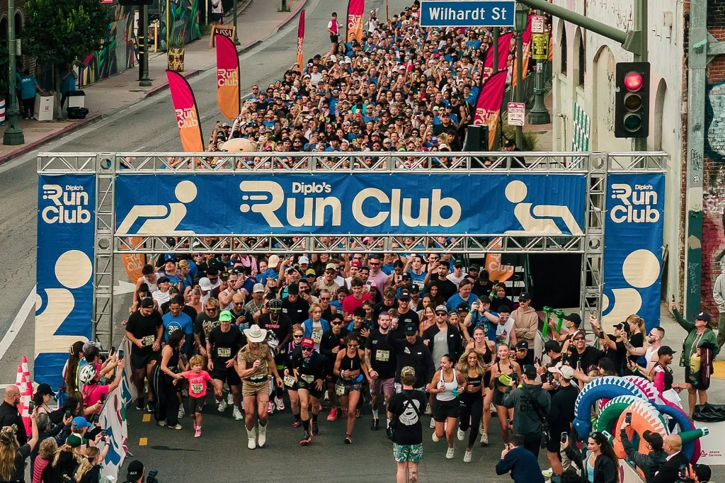 The start line of Diplo's Run Club 5K in Los Angeles, a packed street of runners under the Run Club arch