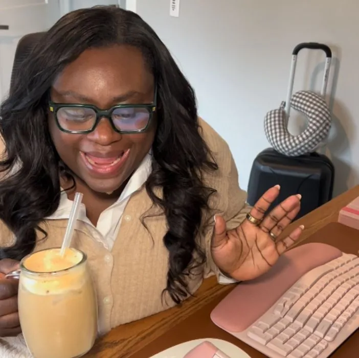 Someone working at a desk with a smoothie and packed luggage, for Engine.