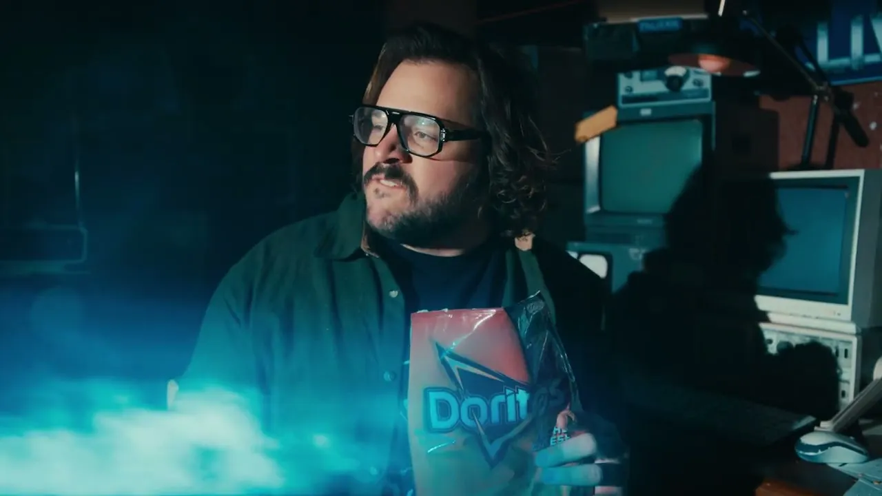 A creator in glasses filming in a dark room