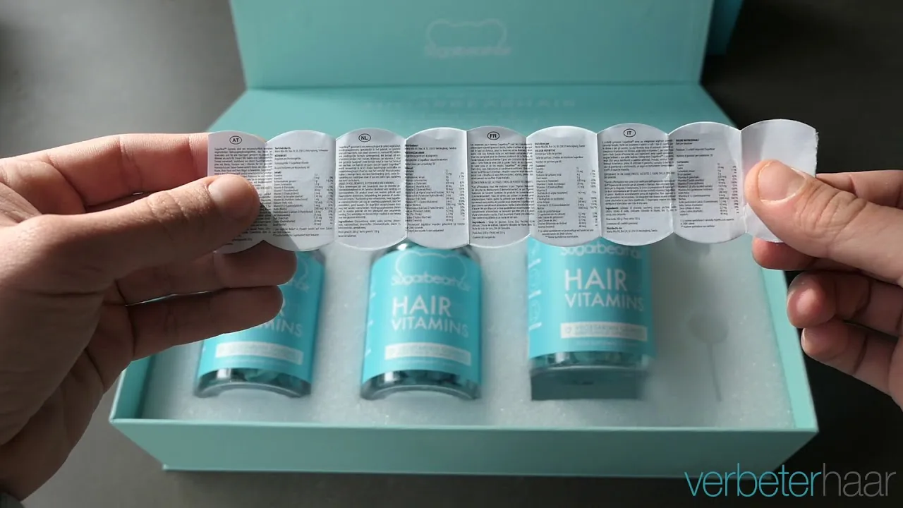 an embossed teal SugarBearHair gift box, three Hair Vitamins bottles nested inside on a foam insert