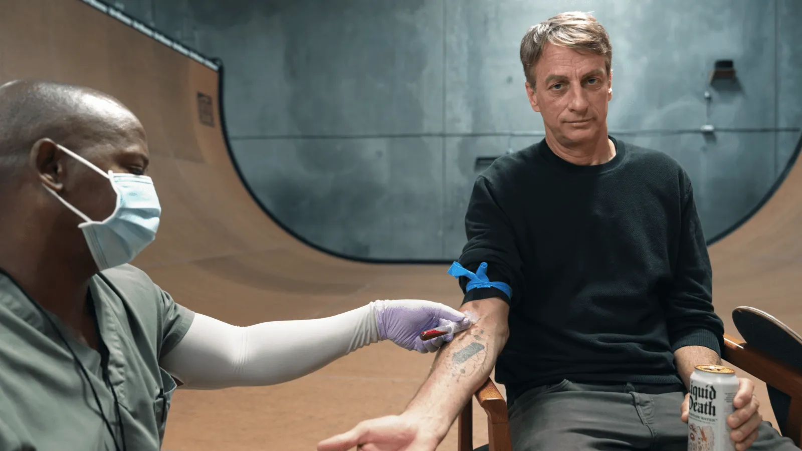 Tony Hawk on a skate ramp holding a can of Liquid Death, the same no-paid-athlete seeding style