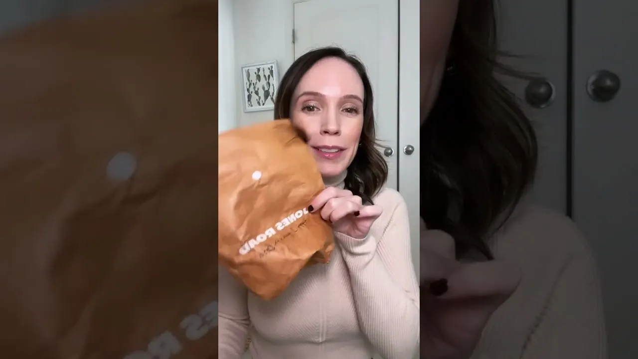 a real creator holding the branded Jones Road kraft seeding bag up to her face on camera