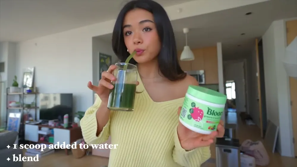 A creator scooping Bloom greens into water in her YouTube video