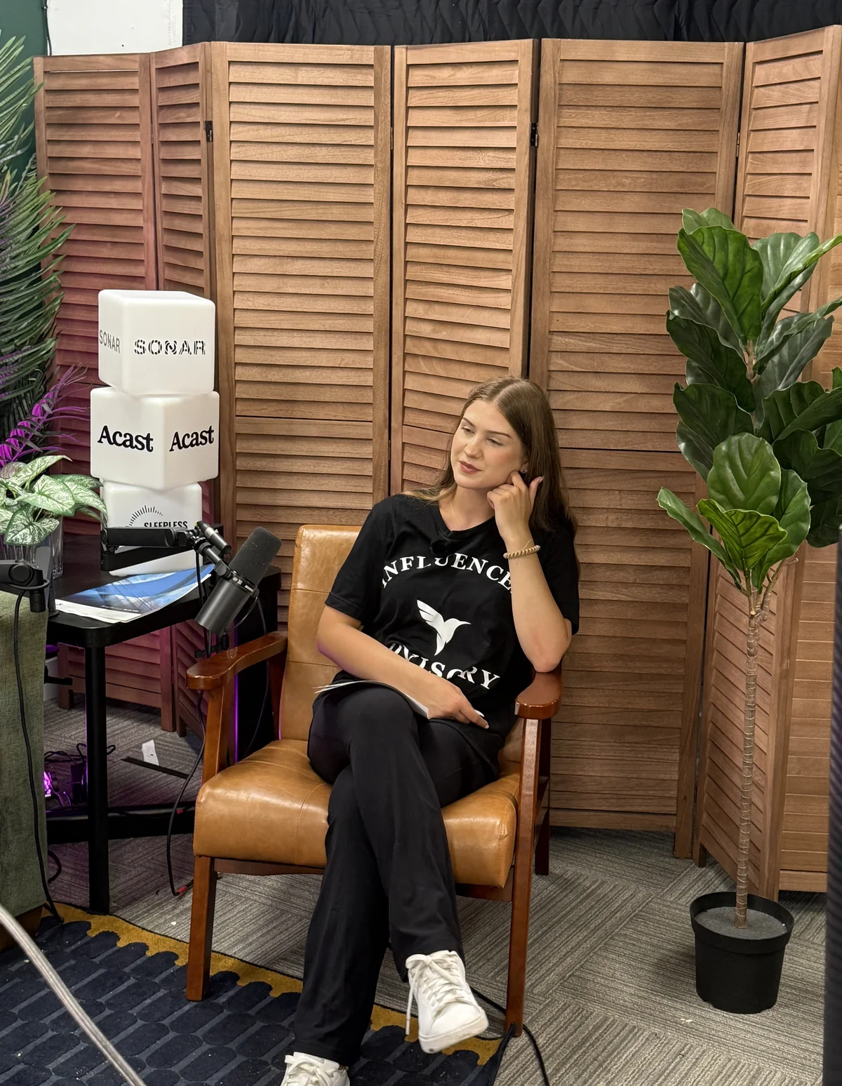 In the chair, on the other side of the microphone.