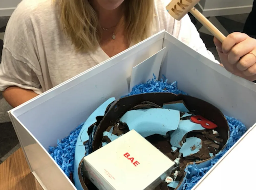 A smashed chocolate heart in its box, the perfume carton in the pieces, a mallet in hand