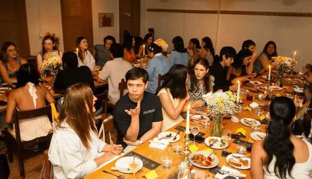 Thirty creators around a long candlelit table