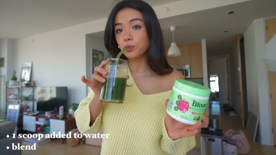 A creator holding a Bloom jar and a glass of greens