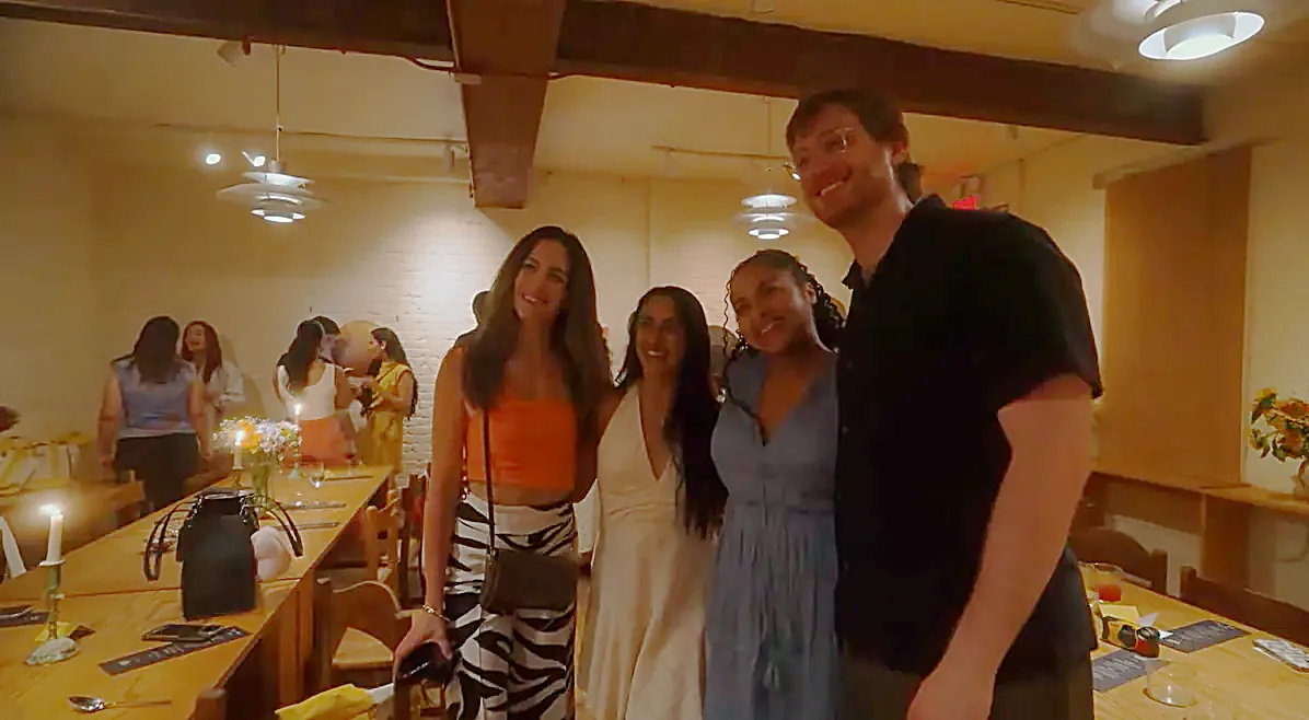 Four guests standing together beside the dinner table, the rest of the room behind them